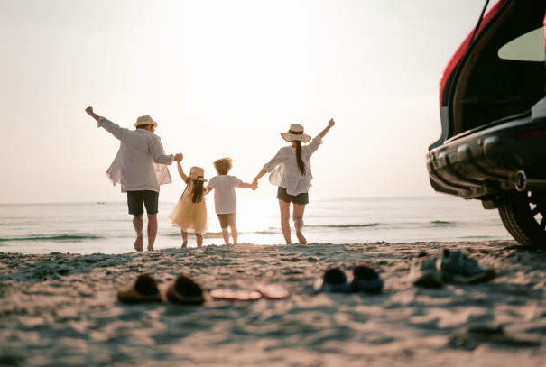 Family vacation holiday, Happy family running on the beach in the sunset. Back view of a happy family on a tropical beach and a car on the side.